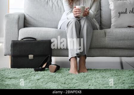 Femme d'affaires se détendant sur le canapé après avoir travaillé à la maison Banque D'Images