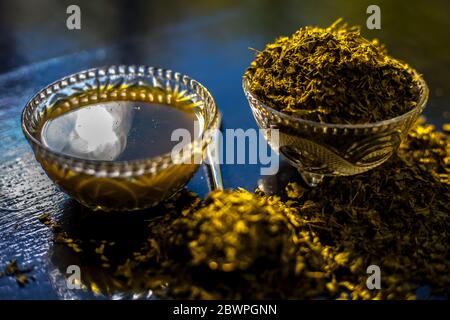 Prise de Kasuri methi cru et de sa pâte fraîchement préparée dans un bol en verre sur une surface noire brillante. Banque D'Images
