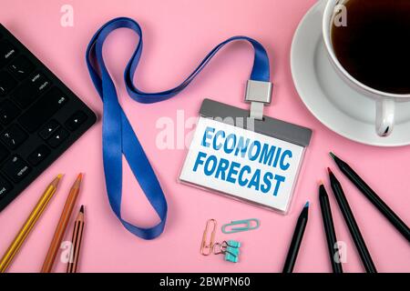 Concept DE PRÉVISION ÉCONOMIQUE. Identité du personnel, crayons de couleur, clavier noir pour ordinateur et une tasse de café sur fond rose Banque D'Images