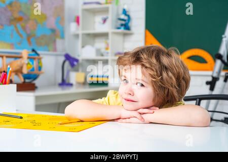 Retour à l'école. Processus éducatif, enfant mignon garçon en classe. Joyeux mignon enfant industriel est assis à un bureau à l'intérieur. Banque D'Images