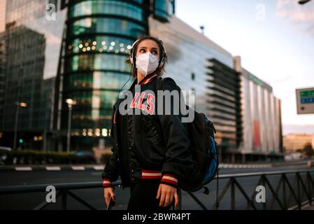 une jeune fille vêtue de sport porte un masque médical dans la rue de la ville en espagne. Pandémie de coronavirus Covid-19 Banque D'Images