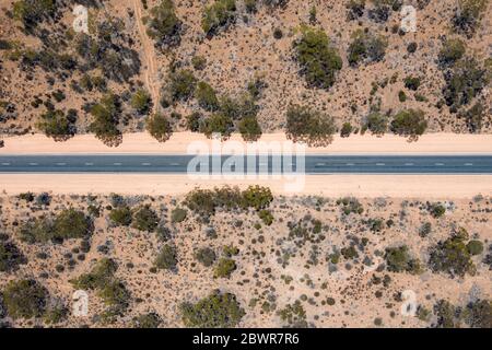 Vue aérienne d'une longue route droite au milieu du sable rose dans l'Outback australien en Australie méridionale Banque D'Images