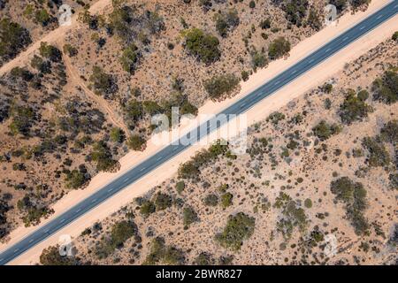 Vue aérienne d'une longue route droite au milieu du sable rose dans l'Outback australien en Australie méridionale Banque D'Images