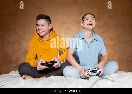 Un gars avec une fille rit, tenant les manettes modifiées sans marques d'identification de la console de jeu dans leurs mains Banque D'Images