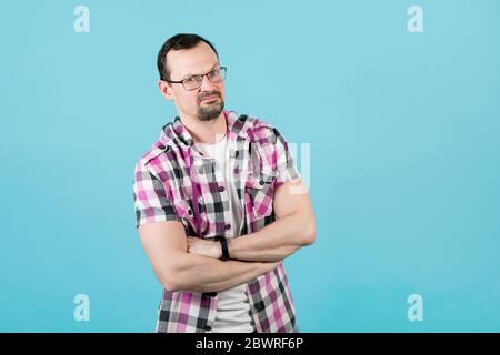 un gars avec une barbe dans une chemise de bureau a plié ses bras sur sa poitrine, une question stupide sur son visage Banque D'Images