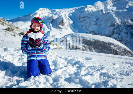 Bonne jeune fille en tenue d'hiver et des friandises de ski, masque tenir la neige en forme d'étoile représentant l'amour montagne concept de vacances Banque D'Images