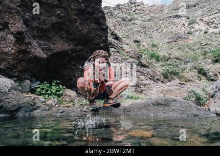 jeune randonneur qui boit de l'eau de ruisseau en montagne Banque D'Images