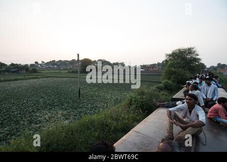 Des hommes au sommet d'un train surpeuplé traversant la campagne dans le Madhya Pradesh, en Inde. Chemins de fer indiens. Banque D'Images