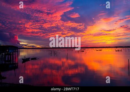 Paysage merveilleux à Lap an Lagoon, Vietnam avec la maison flottante, bateau en bois et ciel coloré étonnant de lever du soleil. Banque D'Images