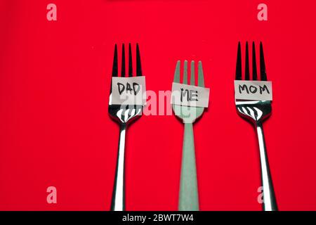 trois fourchettes individuelles séparées pour les aliments familiaux mangeant dans le covid-19 ou le virus corona crise santé médicale quarantaine sur fond rouge Banque D'Images