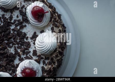 Cerise sur la crème gros plan d'un gâteau au chocolat à la cerise avec de la crème blanche. Cerise rouge, chocolat crème, gâteau éponge à la cerise. Gâteau de bokeh, pâtisserie, vacances Banque D'Images