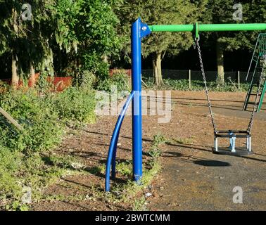 Bleu et vert coloré balançoire pour enfants dans un parc inutilisé pendant le verrouillage Banque D'Images
