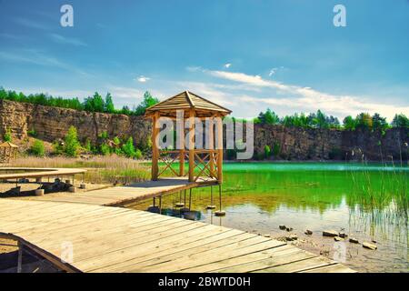 Un lac turquoise au milieu d'un canyon. Concept de voyage et de repos. Une maison au bord du lac, une passerelle en bois qui s'infond dans le lac turquoise. Banque D'Images