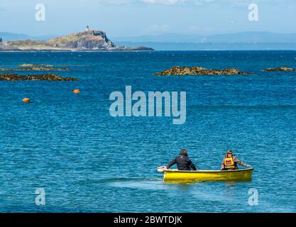 Couple en petit bateau avec moteur hors-bord et vue de Fidra Island, North Berwick, East Lothian, Écosse, Royaume-Uni Banque D'Images