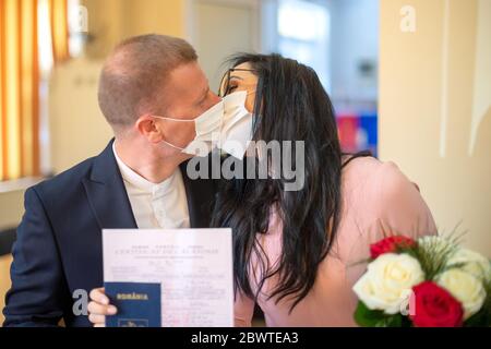 Galati, Roumanie - 10 avril 2020 : couple amoureux, juste marié dans une pandémie de covid. Embrasser avec masque sur le visage et certificat de mariage entre les mains Banque D'Images