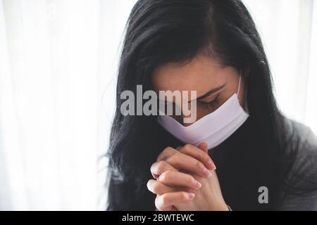 Portrait de la femme avec masque chirurgical priant Banque D'Images