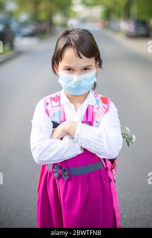 Petite fille d'école qui retourne à l'école après une épidémie pandémique portant un masque facial Banque D'Images