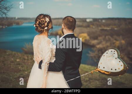 Mariée et marié, debout avec leur dos, se calmer dans flou flou de flou de flou, tenant une boule de gel, avec l'inscription Love Forever, dans le fond d'un Banque D'Images