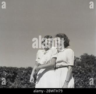 Années 1960, historique, au soleil dehors, une mère se tenant près et regardant fièrement et avec amour une jeune femme, sa fille, Angleterre, Royaume-Uni. Banque D'Images