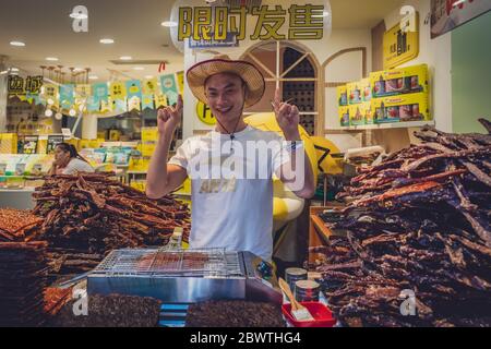 Feng Huang, Chine - août 2019 : heureux Chinois d'âge moyen vendant des portions de viande de porc séchée dans la vieille ville de Fenghuang Banque D'Images