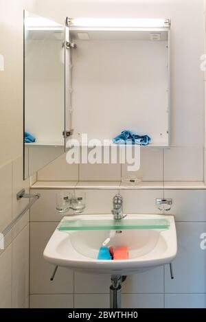 Vue intérieure d'une salle de bains très propre et moderne dans une résidence avec matériel de nettoyage sur le lavabo de la salle de bains Banque D'Images