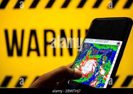 Jaipur, Inde, Circa 2020 - photo d'un téléphone mobile avec cyclone se déplaçant vers la côte. L'arrière-plan est jaune et comporte un signe d'avertissement Banque D'Images