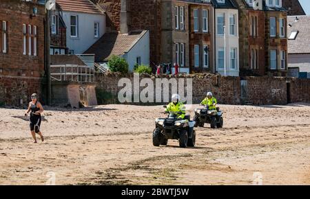 Patrouille de police sur la plage à quatre vélos avec femme jogging, North Berwick, East Lothian, Écosse, Royaume-Uni Banque D'Images