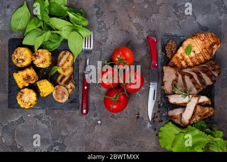 Trois types de frais steak grillé (poulet, porc, boeuf) sur la plaque d'ardoise aux épinards, tomates et pommes de terre grillées sur fond de pierre avec copie espace, Banque D'Images