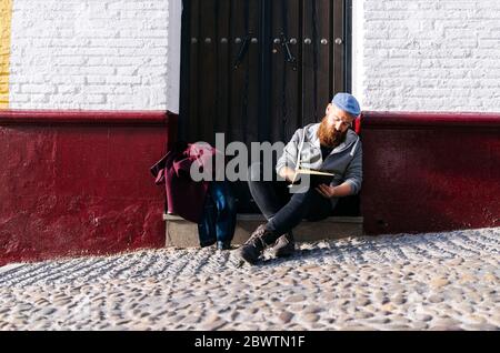 Homme assis sur le devant de la ville en dessinant un croquis, Grenade, Espagne Banque D'Images