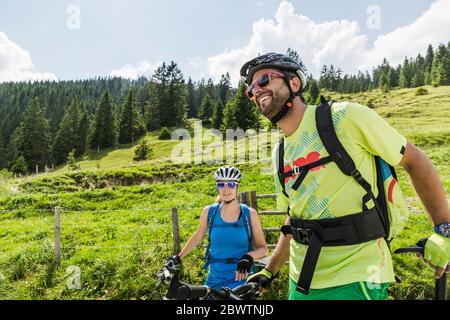 Couple heureux avec VTT dans un pré dans les montagnes, Achenkirch, Autriche Banque D'Images