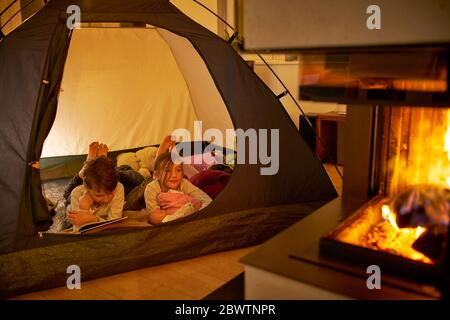 Le camping frère et sœur dans le salon près du foyer Banque D'Images