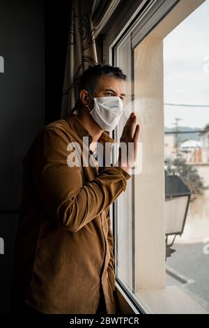 Homme portant un masque de protection et regardant par la fenêtre Banque D'Images