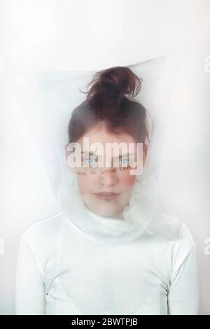Portrait de la jeune femme à tête rouge portant un masque transparent avec question Banque D'Images