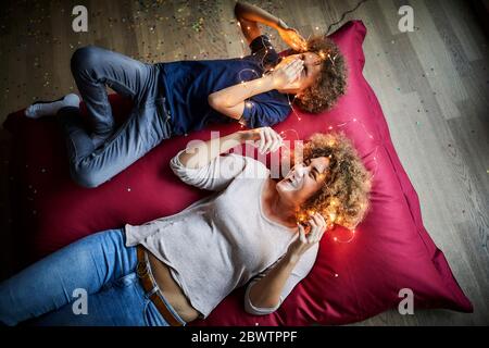 Mère et fils couchés sur le sol, jouant avec des lumières de fées Banque D'Images