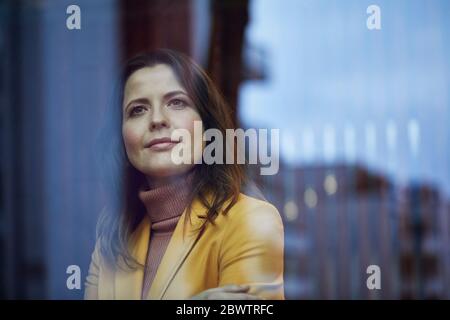 Portrait of smiling businesswoman looking out of window Banque D'Images