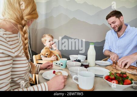 Portrait d'un petit garçon assis à la table du petit déjeuner avec ses parents Banque D'Images