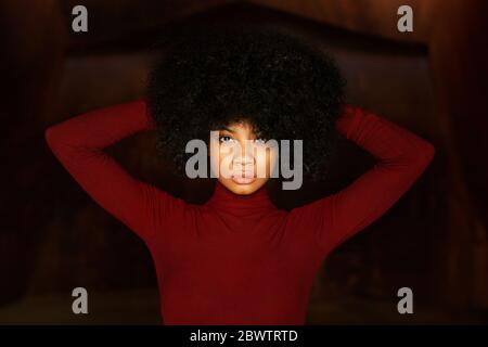 Portrait de la jeune femme en body rouge, mains dans les cheveux Banque D'Images