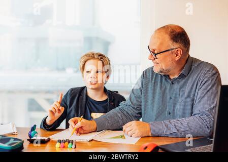 Père aidant son fils à faire ses devoirs à son bureau Banque D'Images