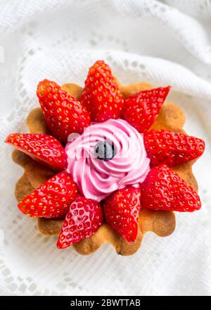 beau gâteau savoureux de gros plan avec fraises, chèvrefeuille et crème rose Banque D'Images