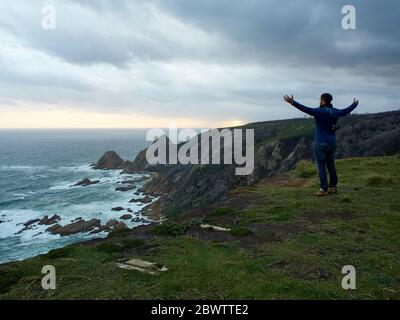 Homme profitant de la vue depuis les falaises et l'océan au coucher du soleil, Plettenberg Bay, Afrique du Sud Banque D'Images