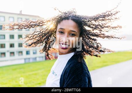 Portrait d'une jeune femme avec des anglaises qui lui laissent les cheveux au contre-jour Banque D'Images