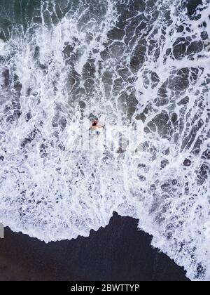 Indonésie, Bali, Plage de Pererenan, vue aérienne du surfeur solitaire entrant dans l'eau Banque D'Images