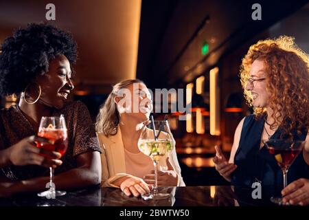 Des amis heureux se sont sociés dans un bar avec des cocktails Banque D'Images