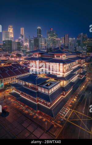 Singapour, temple et musée de la relique de la dent de Bouddha la nuit avec gratte-ciel en arrière-plan Banque D'Images
