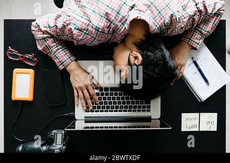 Femme surtraitée dormant sur un ordinateur portable dans le bureau à domicile Banque D'Images