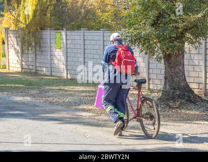 Alberton, Afrique du Sud - cycliste mâle non identifié poussant son vélo avec des achats et une image de sac à dos en format horizontal Banque D'Images