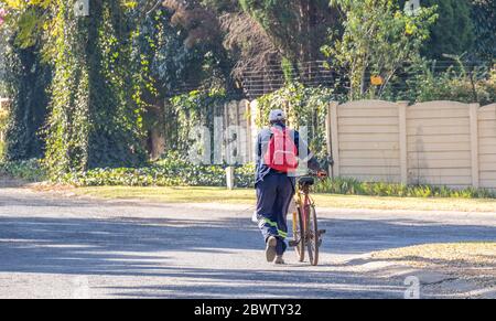 Alberton, Afrique du Sud - cycliste mâle non identifié poussant son vélo avec des achats et une image de sac à dos en format horizontal Banque D'Images