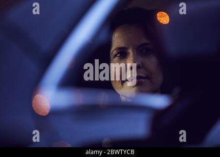 Reflet d'une femme dans le rétroviseur d'une voiture la nuit Banque D'Images