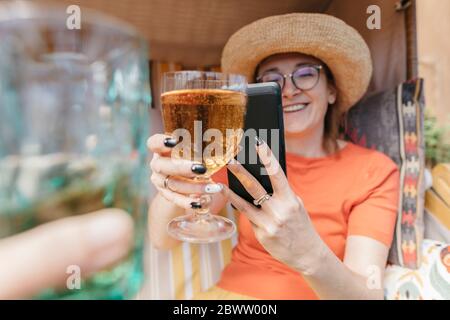 Bonne femme mûre sur la terrasse prenant la photo d'un verre de limonade avec un smartphone Banque D'Images