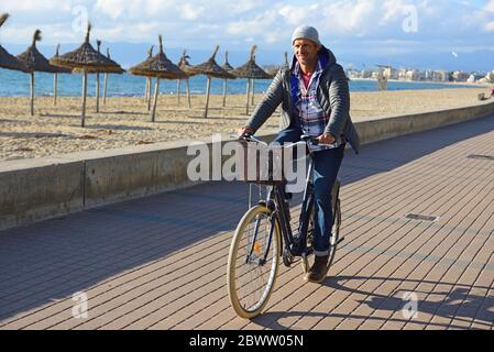 Homme à vélo sur la promenade de la plage en hiver Banque D'Images